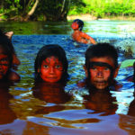 Demarcada há 30 anos, a terra Yanomami continua sob ameaça crescente. Distribuída entre os estados de Roraima e Amazonas, a maior terra indígena do país vive seu pior momento de garimpo ilegal desde a homologação do território, segundo a Hutukara Associação Yanomami. Em relatório de 2021, a associação aponta a invasão garimpeira como causa de violações sistemáticas de direitos humanos das comunidades que vivem ali, com impactos e consequências assustadores.  Em viagem no mês de julho pelo Rio Maturacá, no Amazonas, o fotógrafo especializado em povos indígenas Renato Soares captou um momento de extrema beleza envolvendo jogo e vida: a brincadeira de crianças yanomami nas águas limpas e ainda livres de mercúrio do rio.