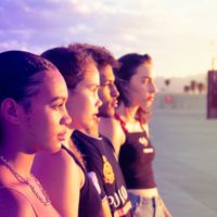 Quatro adolescentes de perfil olham ao longe