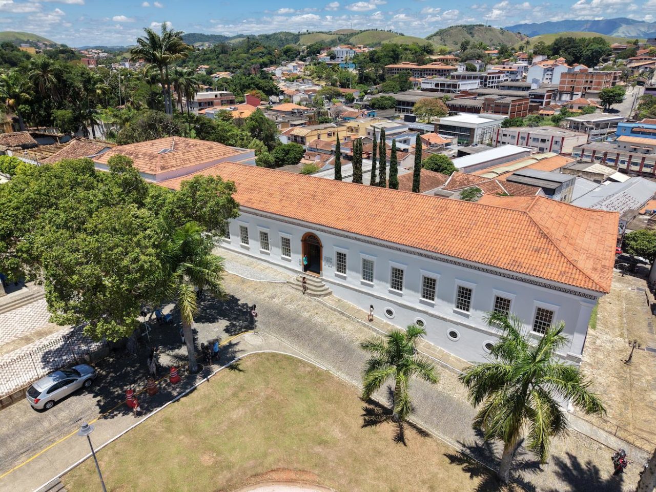 vista aérea do Museu Vassouras, grande prédio branco em estilo colonial, com árvores à frente e a cidade de Vassouras ao fundo