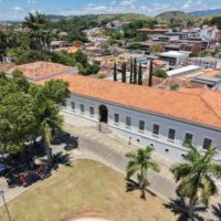 vista aérea do Museu Vassouras, grande prédio branco em estilo colonial, com árvores à frente e a cidade de Vassouras ao fundo