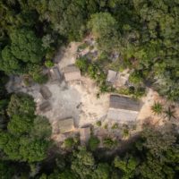 Vista aérea de casas tradicionais indígenas nas proximidades de Manaus (AM). A foto mostra o telhado de oito casas de diferentes tamanhos em um clarão da floresta